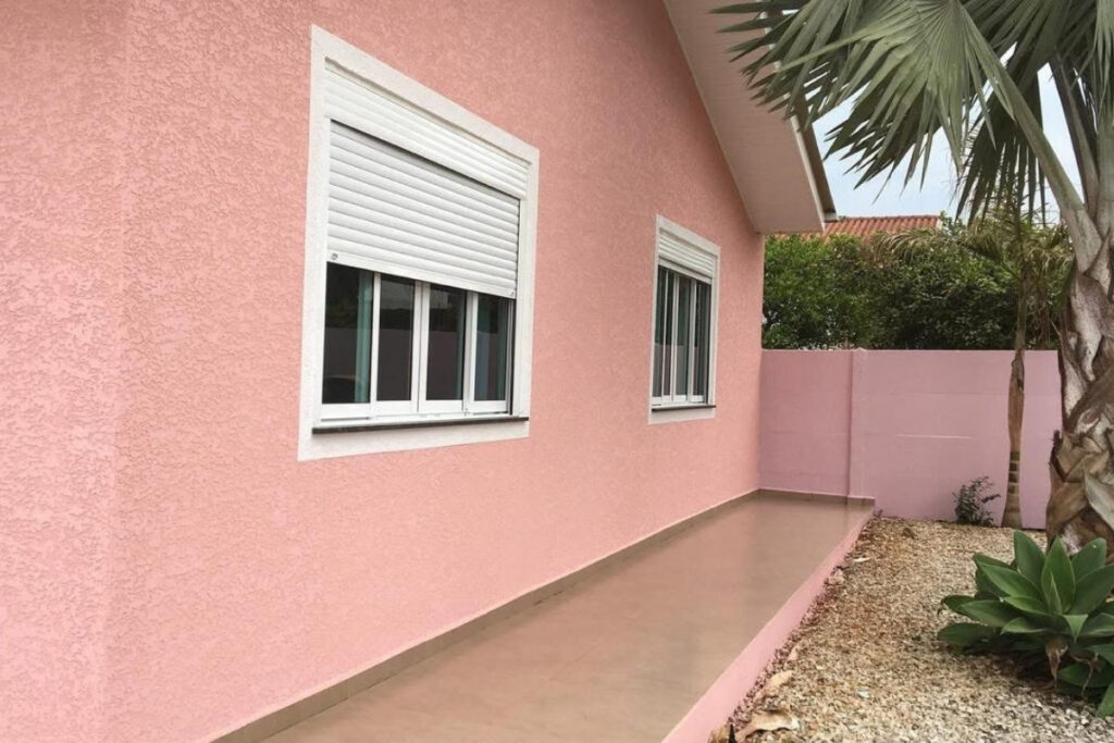 Detalhe técnico de aplicação de textura arenito simulação de areia fina em muro residencial de luxo na Vila Carrão.