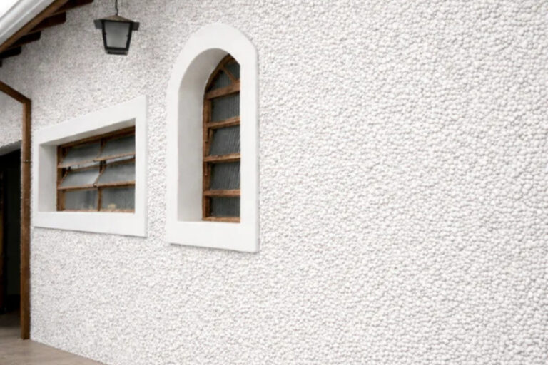 Detalhe técnico aproximado de amostra de granilha mineral natural aplicada em muro residencial de luxo na região do Tatuapé.