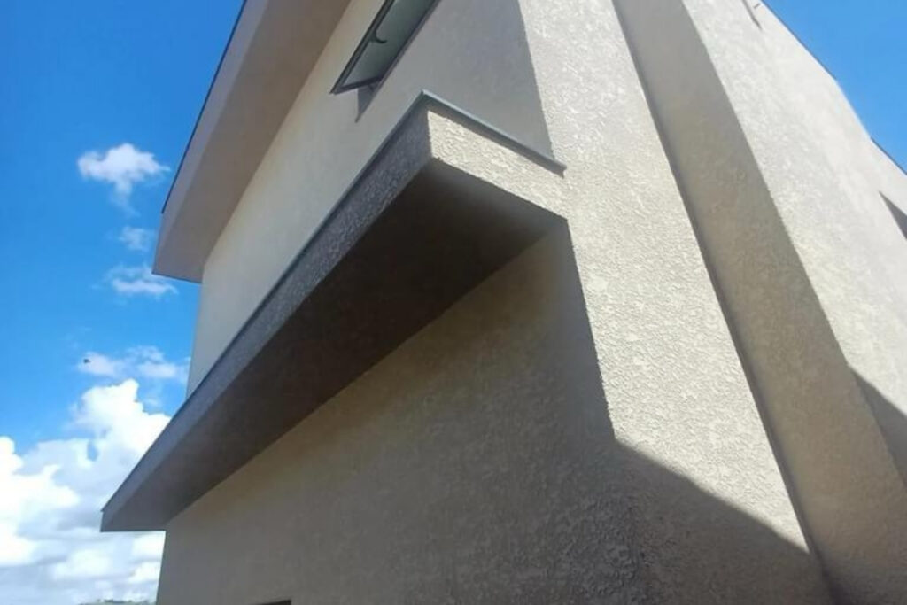 Fachada residencial moderna na Vila Formosa com aplicação de textura projetada cinza e proteção de resina acrílica Big Texturas