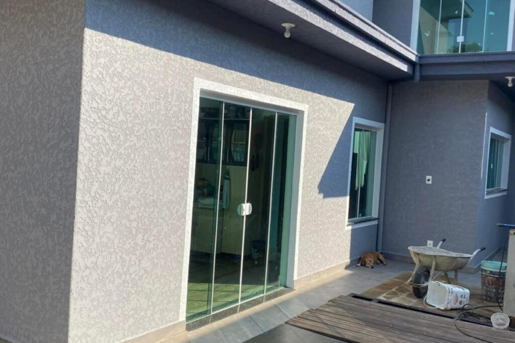 Detalhe técnico de aplicação de revestimento arenato decorativo em parede externa de imóvel residencial na Vila Zelina.