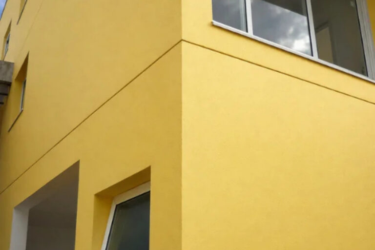 Detalhe técnico da aplicação de textura de parede acrílica em fachada residencial na região de São Mateus.