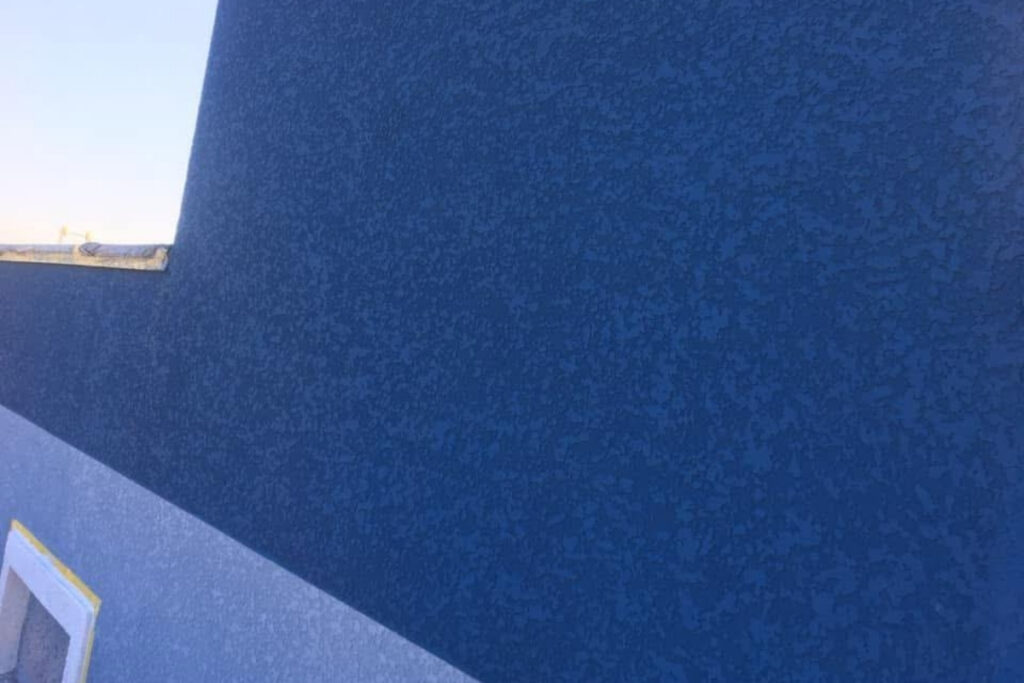 Fachada de sobrado de alto padrão no Tatuapé com acabamento em revestimento de quartzo cinza e iluminação decorativa Big Texturas.